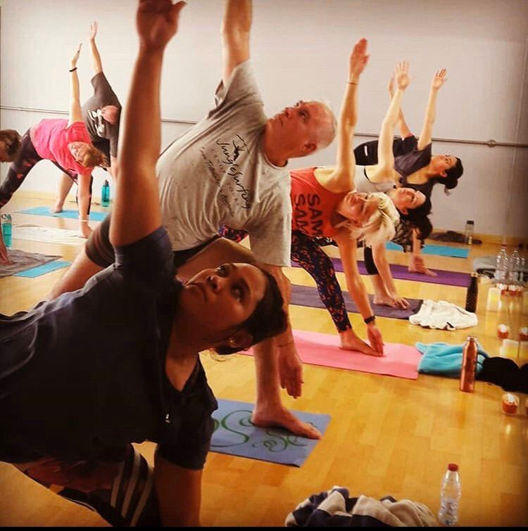 Sunlit heated yoga studio with rows of mats and warm infrared panels
